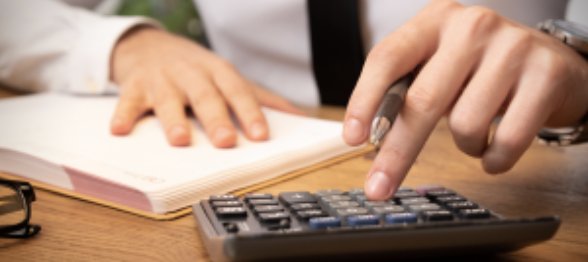 Manos usando una calculadora junto a una agenda